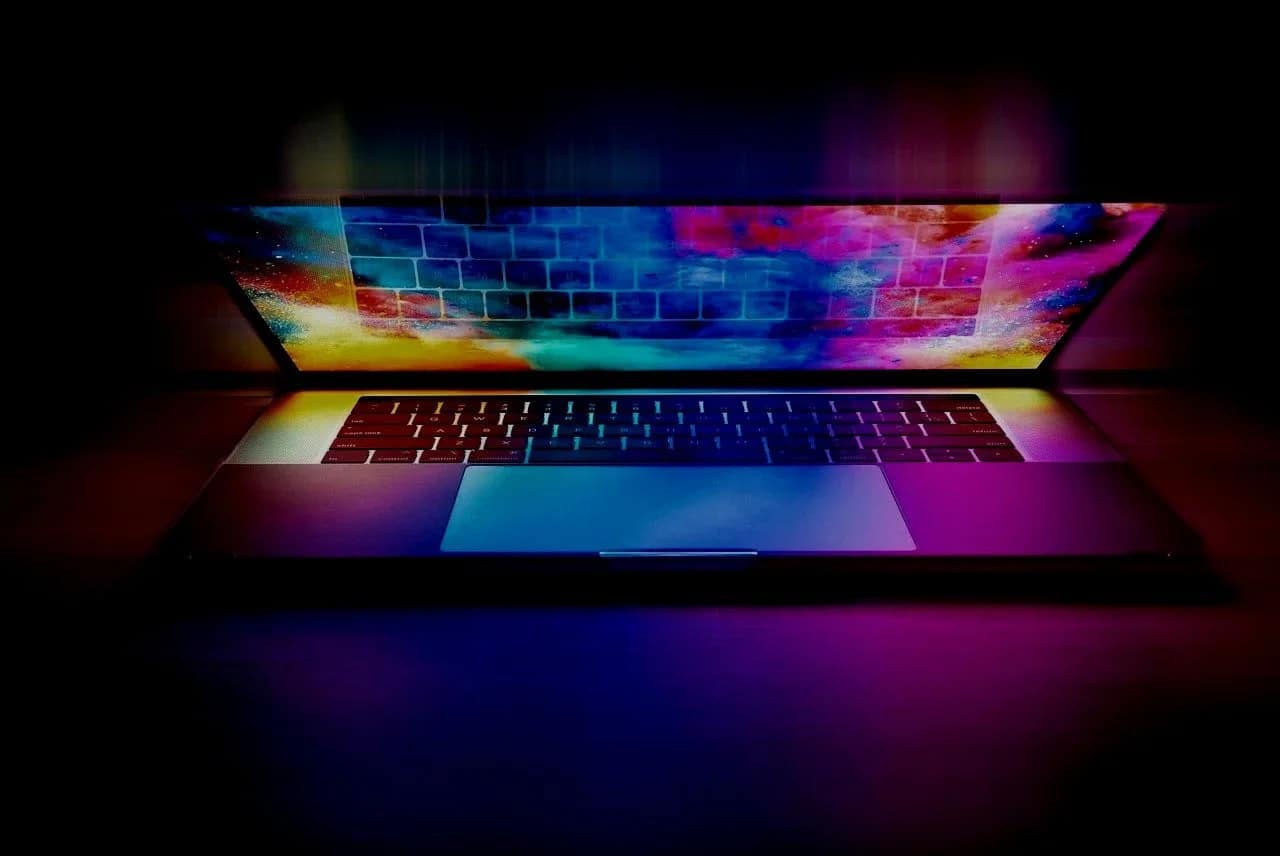 Open laptop illuminated by colorful neon lighting